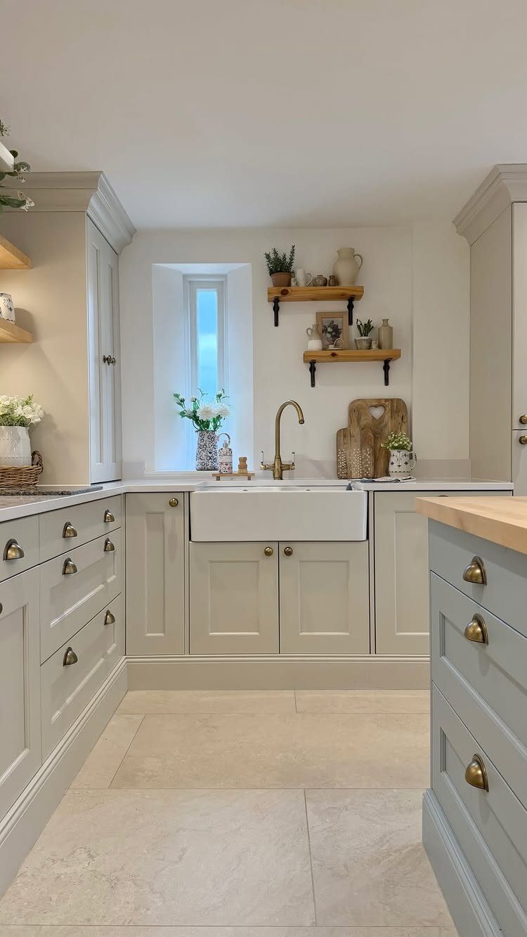 Light grey kitchen cabinets with dark rustic hardware and a white farmhouse sink.