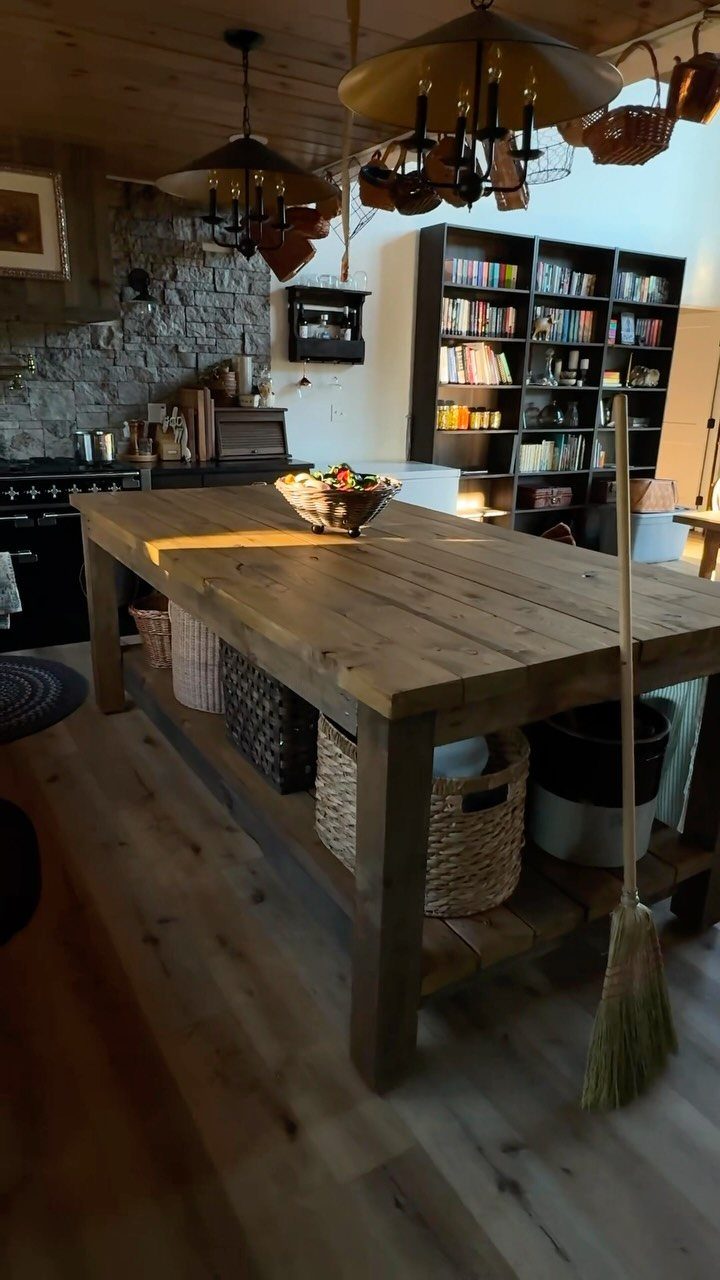 Large wooden kitchen island with storage baskets on a light wood floor.