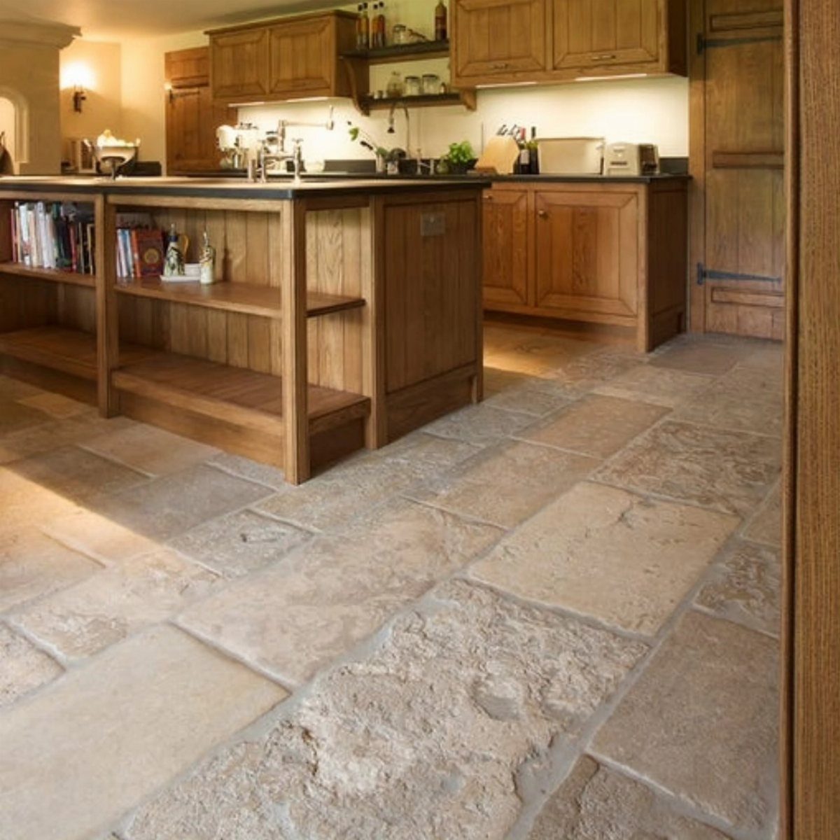 Textured beige natural stone flooring in a rustic kitchen with wooden cabinetry.