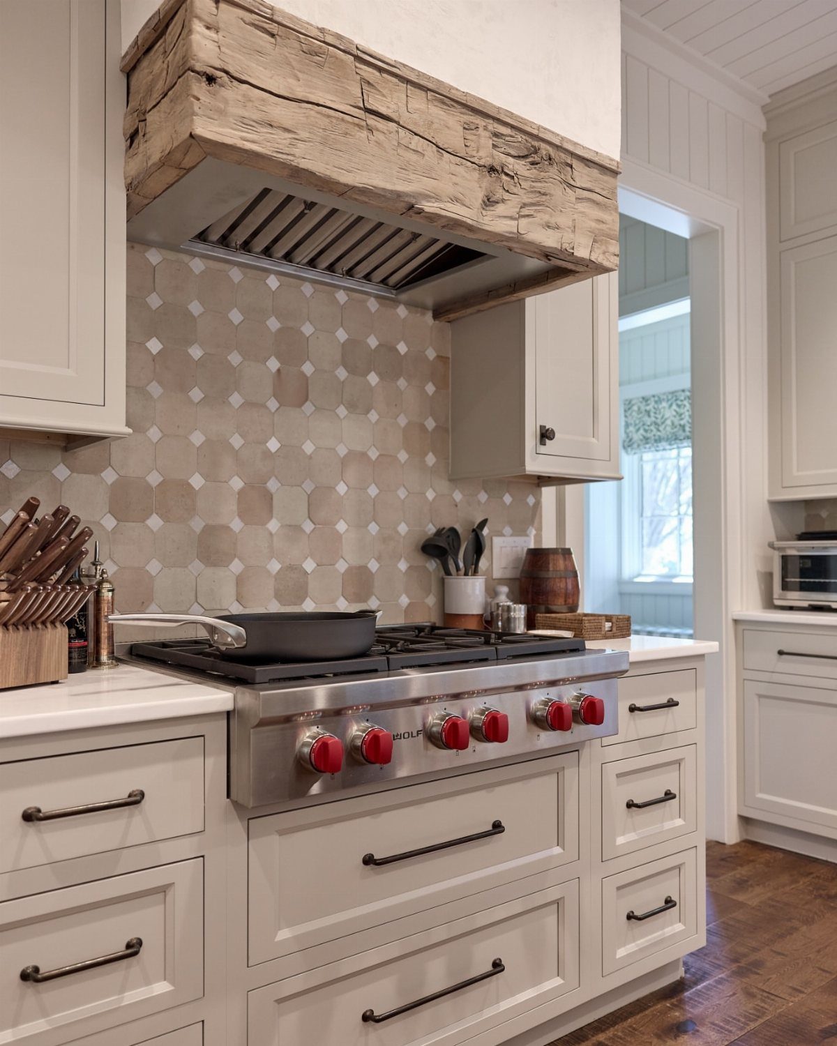 Rustic range hood encased in reclaimed wood above a professional stainless steel stove.