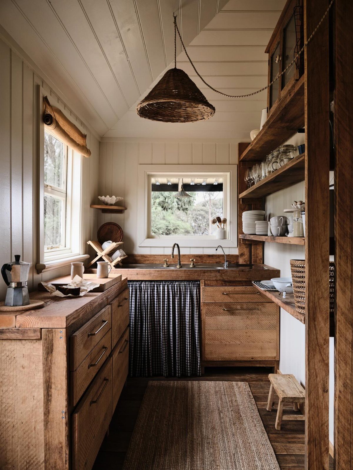 Rustic kitchen with reclaimed wood cabinets, open shelving, and a woven pendant light.