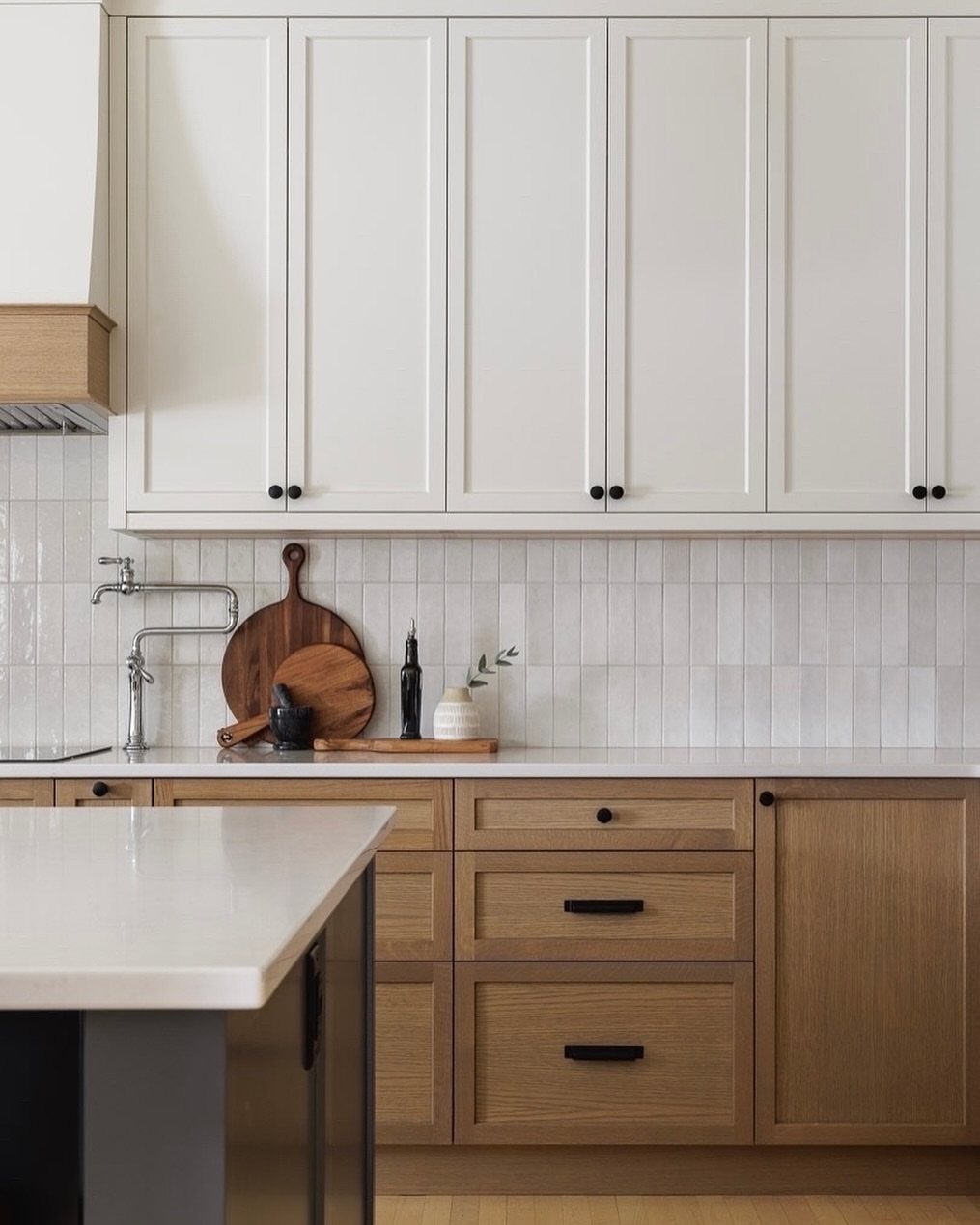 White upper cabinets and light wood lower cabinets in a rustic kitchen