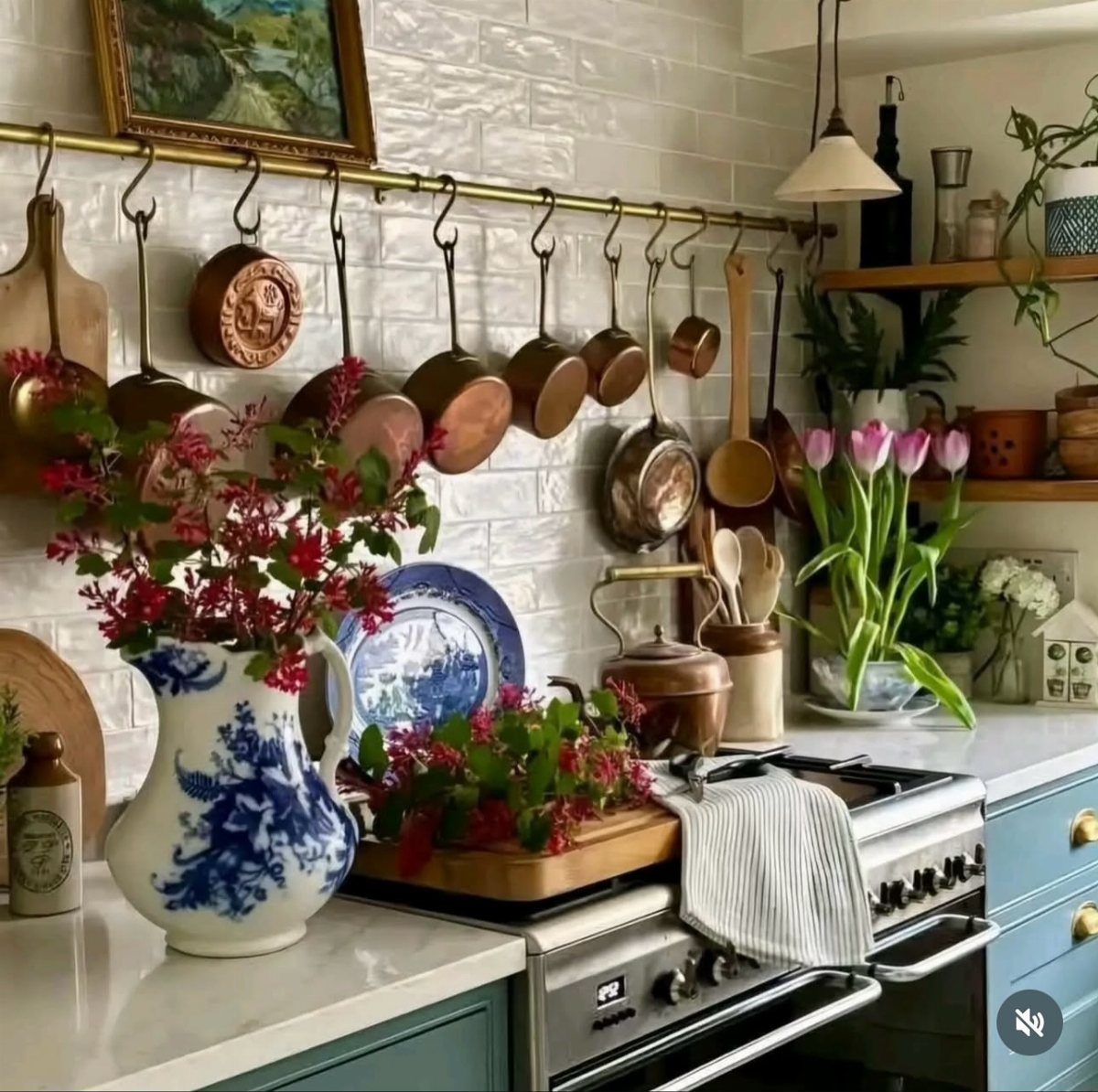 Copper pots and pans hanging from a brass rail in a rustic kitchen