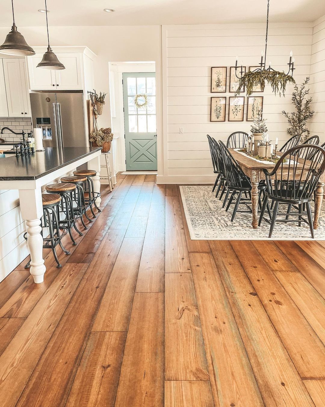 Warm wood plank flooring in a rustic kitchen with white cabinetry and dining area