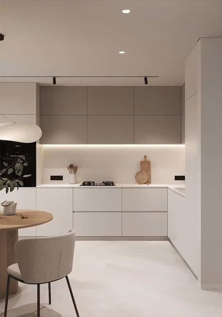 Modern white kitchen with hardware-free cabinets, white countertops, and a round wooden table.