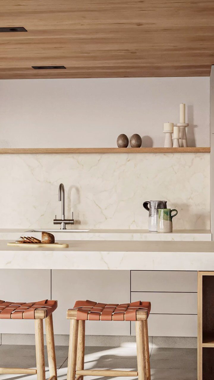 Cream-colored kitchen cabinets and beige countertops with leather-topped wooden stools in foreground.