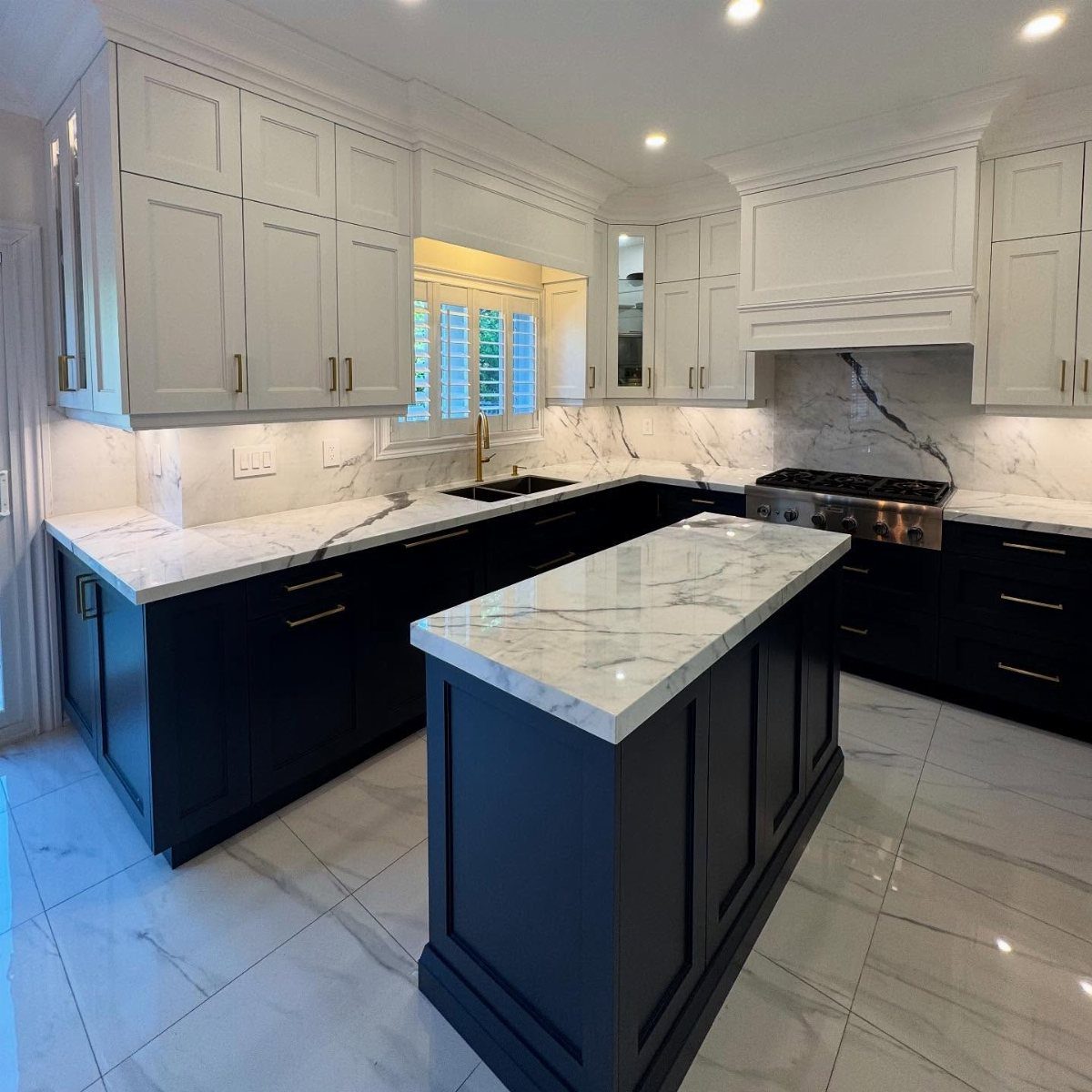 Kitchen with white upper cabinets, navy blue lower cabinets, and white marble countertops.