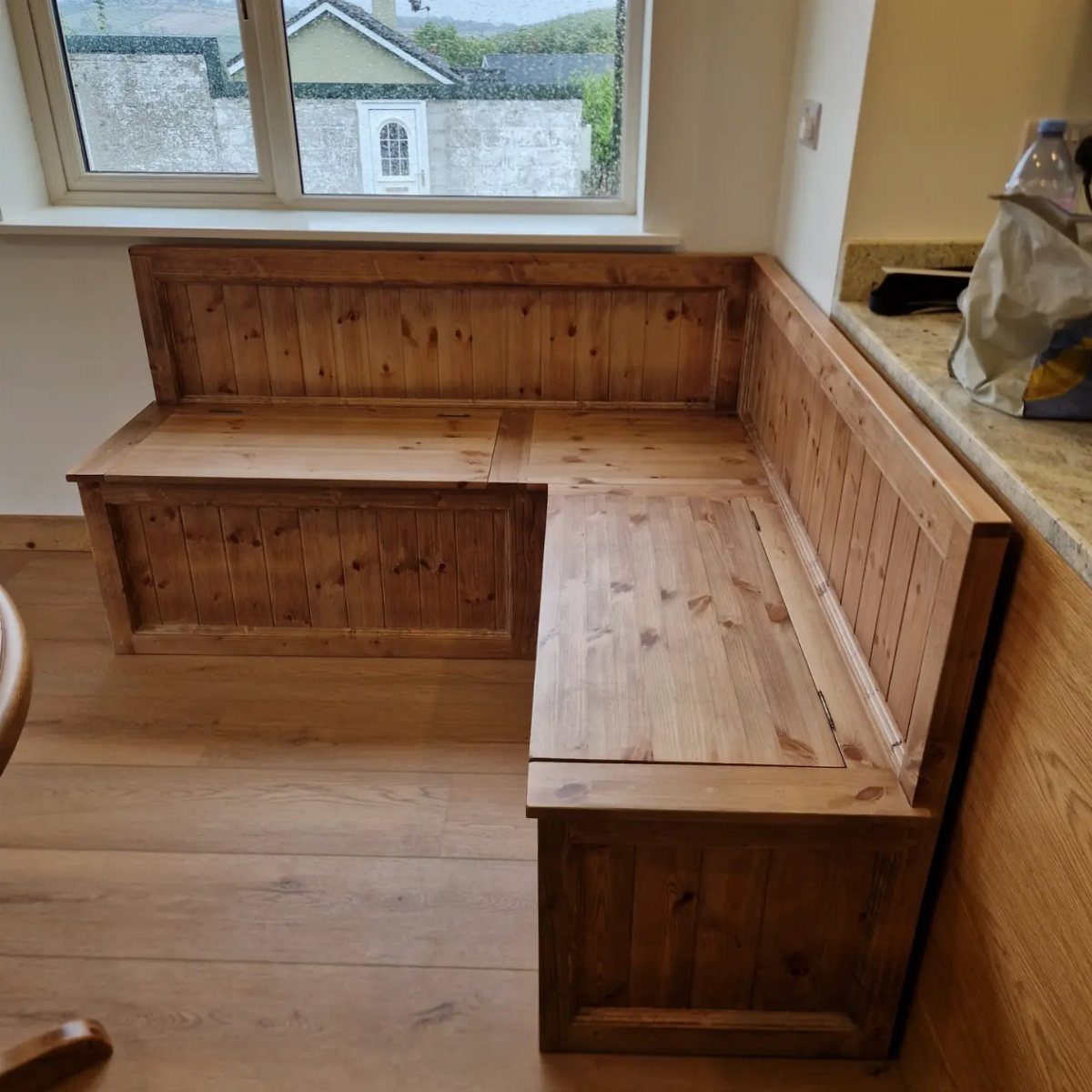 L-shaped wooden corner bench with storage compartments in a bright kitchen nook