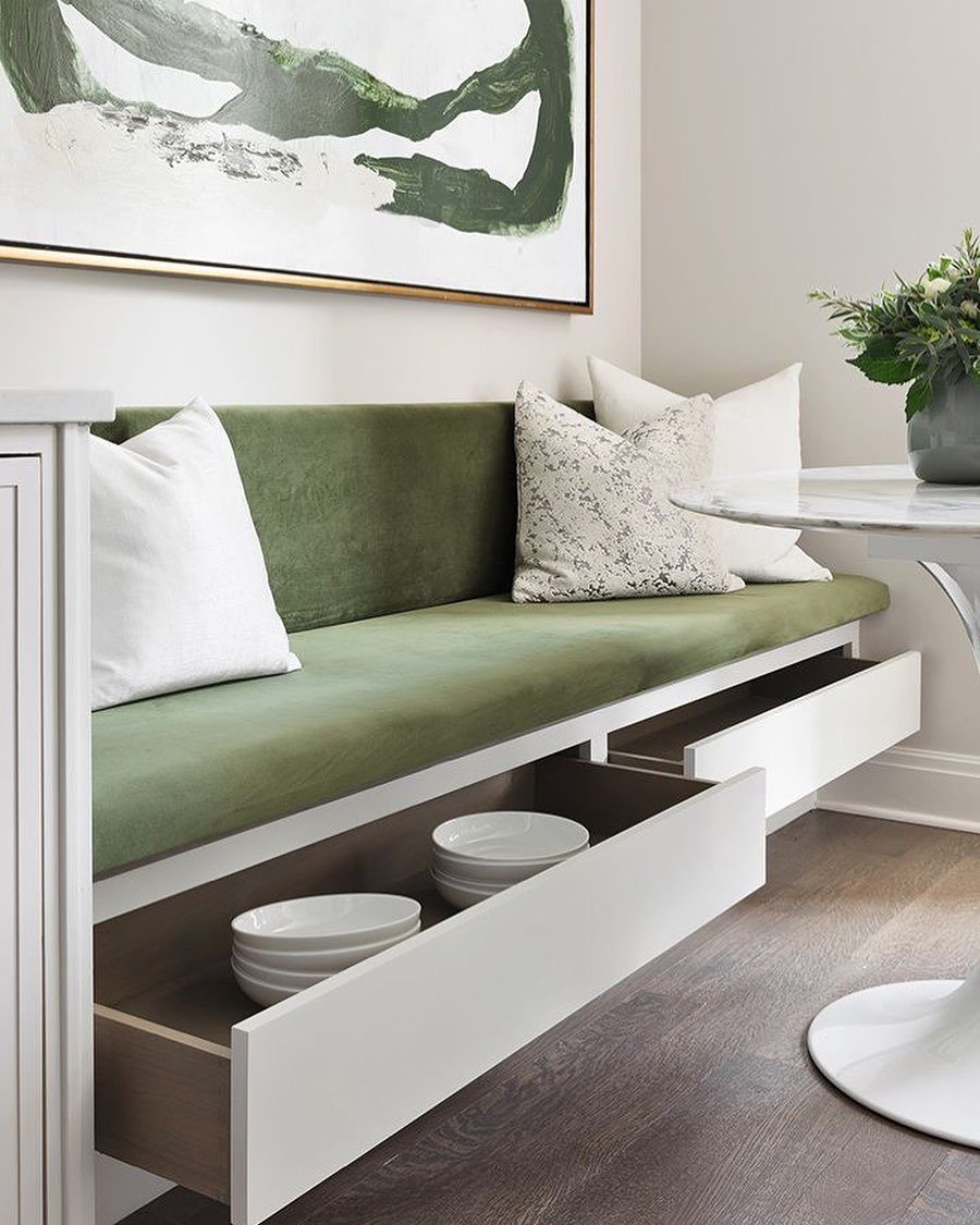 Green upholstered kitchen banquette with white storage drawers pulled out from underneath the seat.