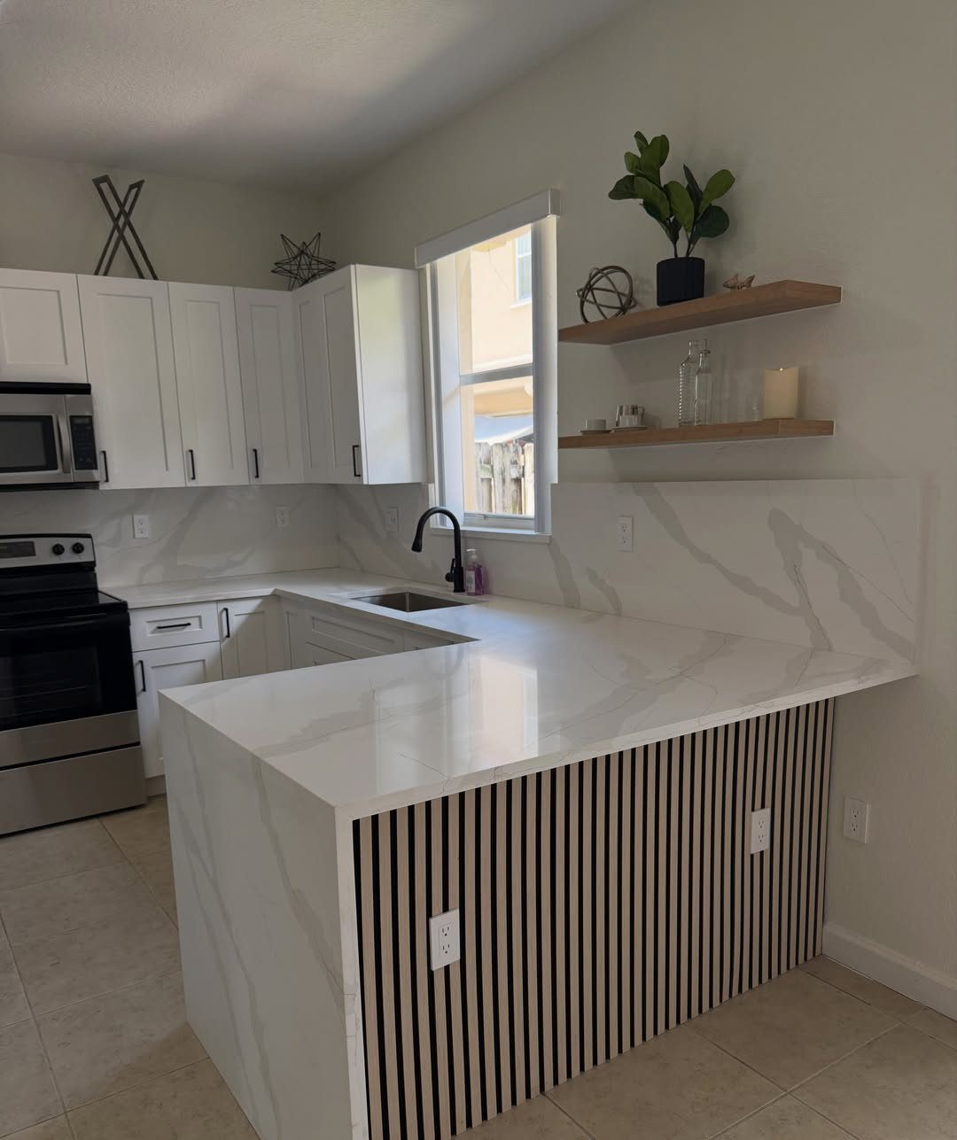 15 Kitchen Style L Shape Ideas, from Islands to Backsplashes 15 White L-shaped kitchen with marble countertops, a peninsula, and wooden floating shelves.