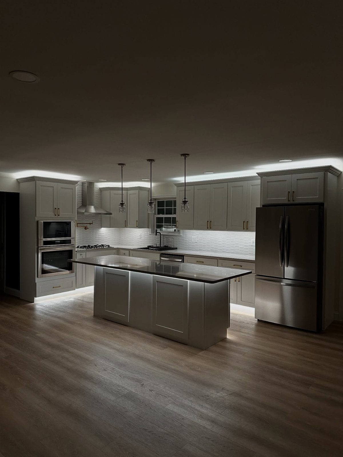 15 Kitchen Style L Shape Ideas, from Islands to Backsplashes 9 Modern grey kitchen with glowing under-cabinet lighting illuminating the white countertops and island.