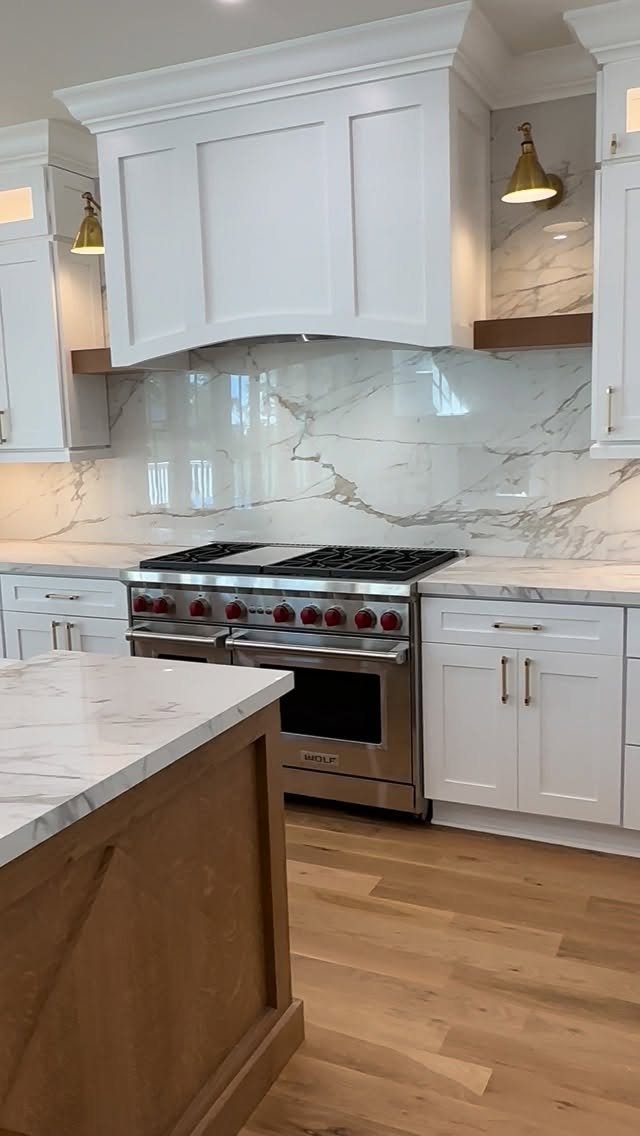 15 Kitchen Style L Shape Ideas, from Islands to Backsplashes 12 Natural wood kitchen island with marble countertop next to white cabinets and stove.