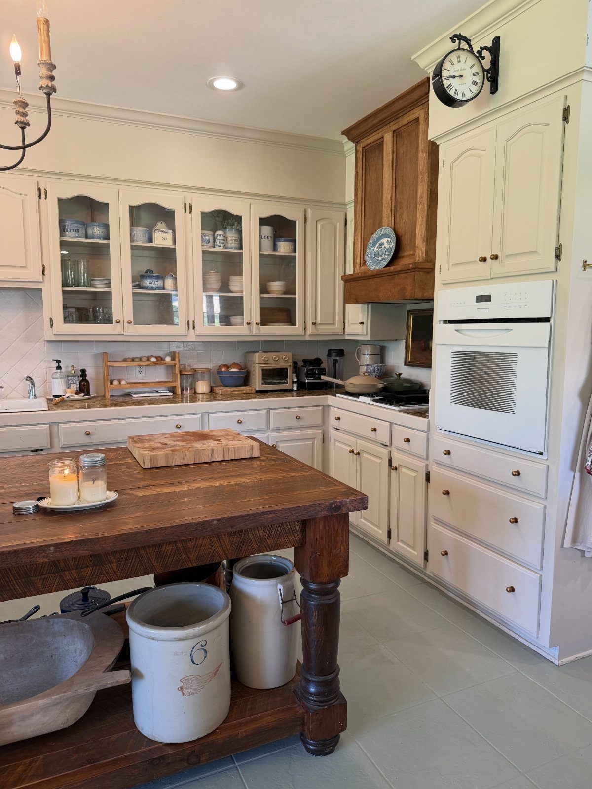 15 Kitchen Style L Shape Ideas, from Islands to Backsplashes 14 Wooden worktable island in a kitchen with cream cabinets and glass-front cupboards.