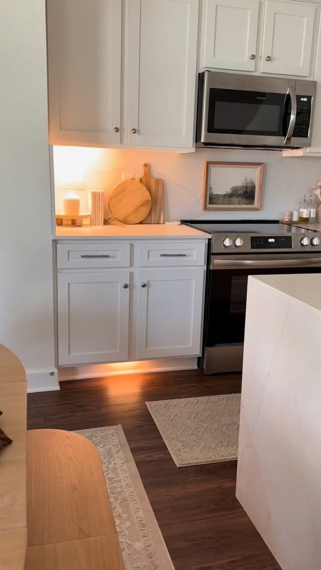 12 Kitchen Updates on a Budget, From Hardware to Pantry Jars 9 White kitchen cabinets and stainless steel appliances with a wooden cutting board.