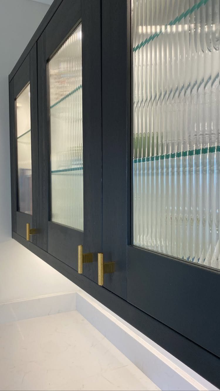 12 Kitchen Updates on a Budget, From Hardware to Pantry Jars 6 Dark grey kitchen cabinets with reeded glass doors and gold hardware.