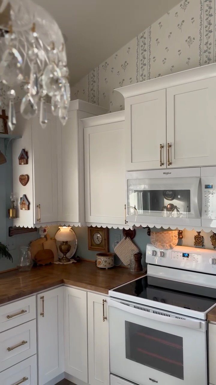 12 Kitchen Updates on a Budget, From Hardware to Pantry Jars 5 White kitchen cabinets with gold handles and decorative scalloped trim along the bottom edge.