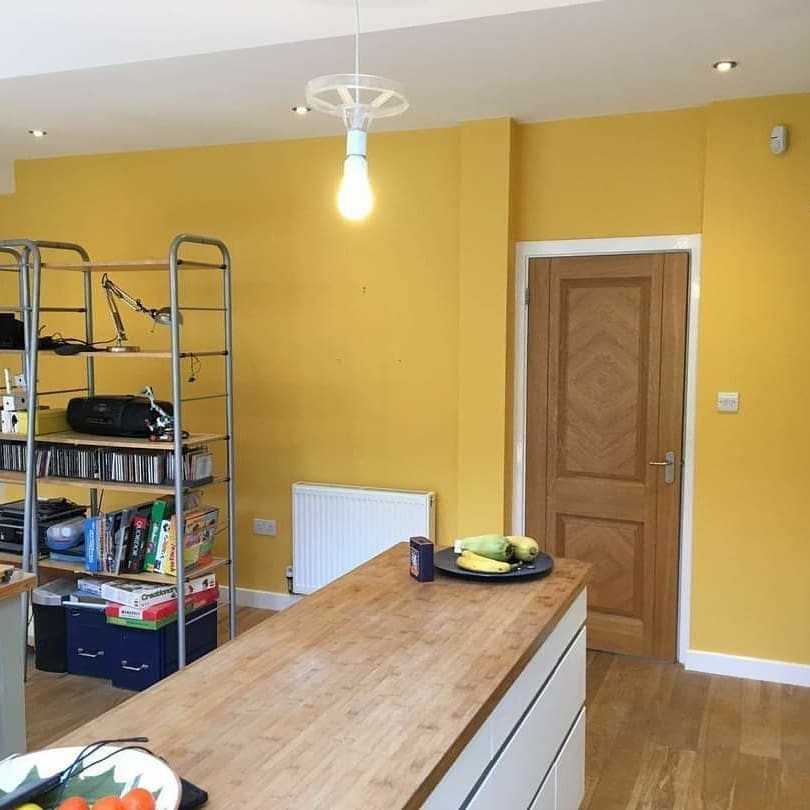 12 Kitchen Updates on a Budget, From Hardware to Pantry Jars 10 Bright yellow kitchen walls with a wooden island and metal storage shelving.