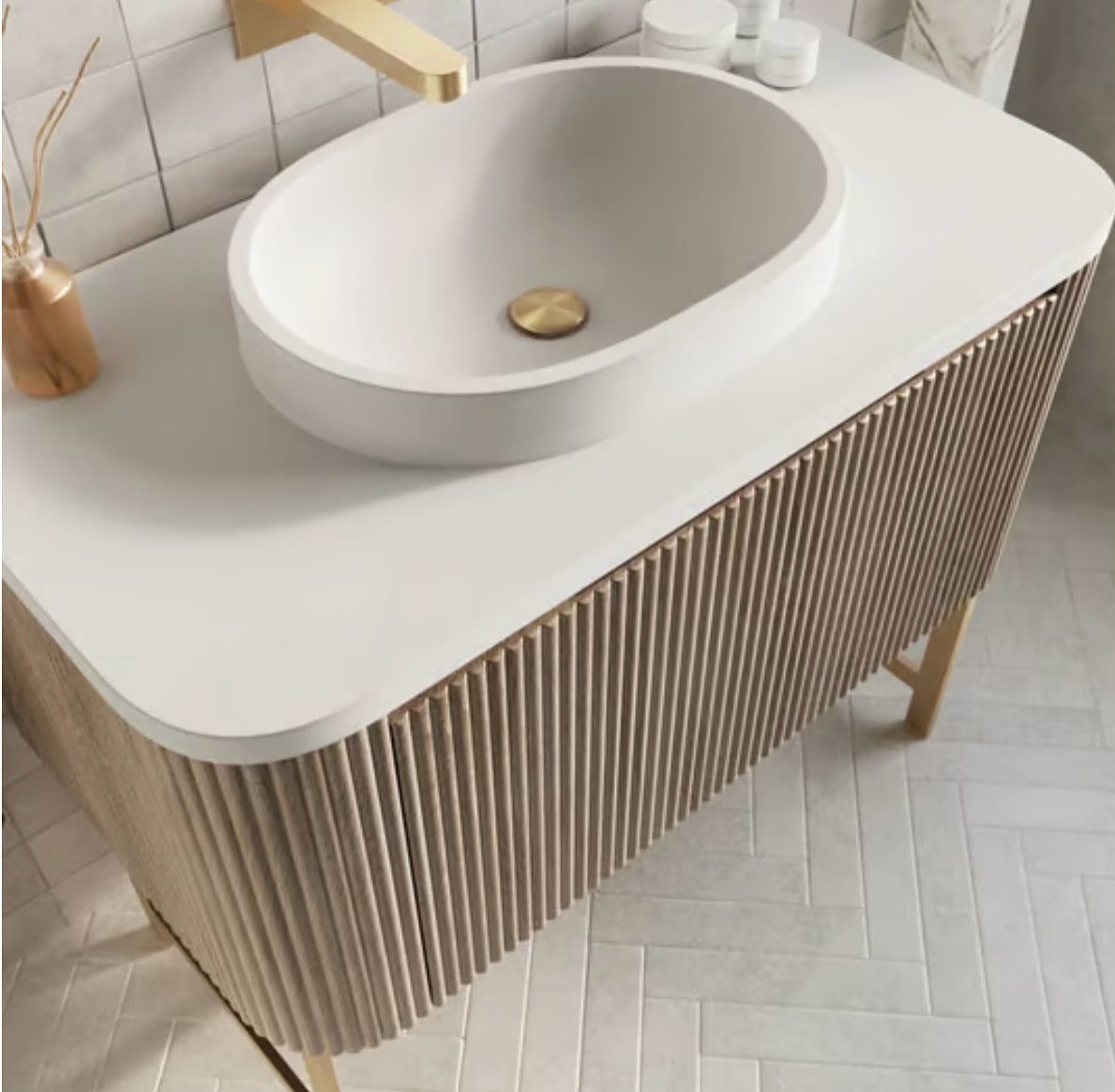 White vessel sink on a vanity with light wood fluted cabinet fronts.