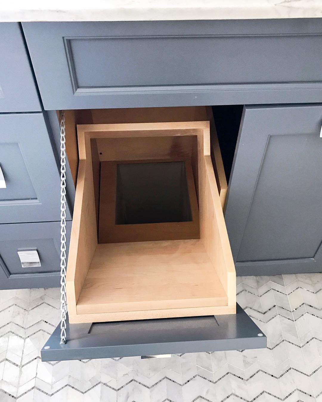 Pull-out wooden laundry hamper concealed within a grey bathroom vanity cabinet.