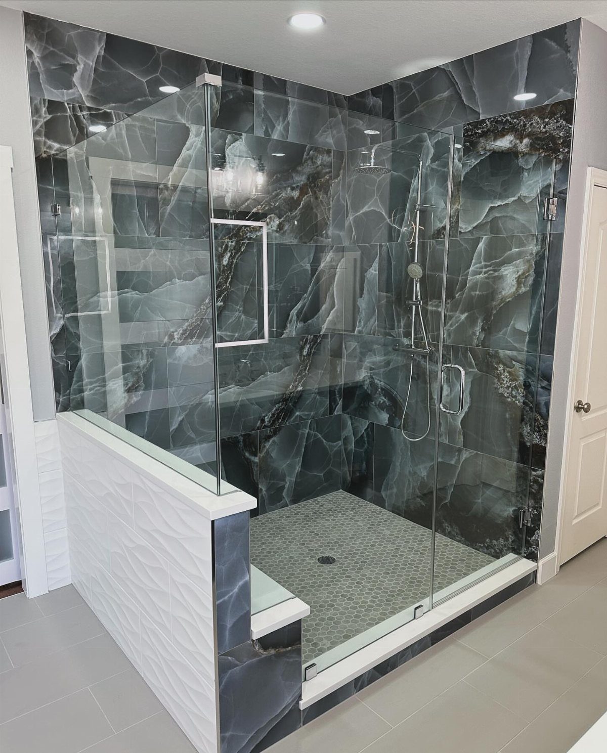 Walk-in shower with dark marbled tile walls and a built-in stone shower bench.