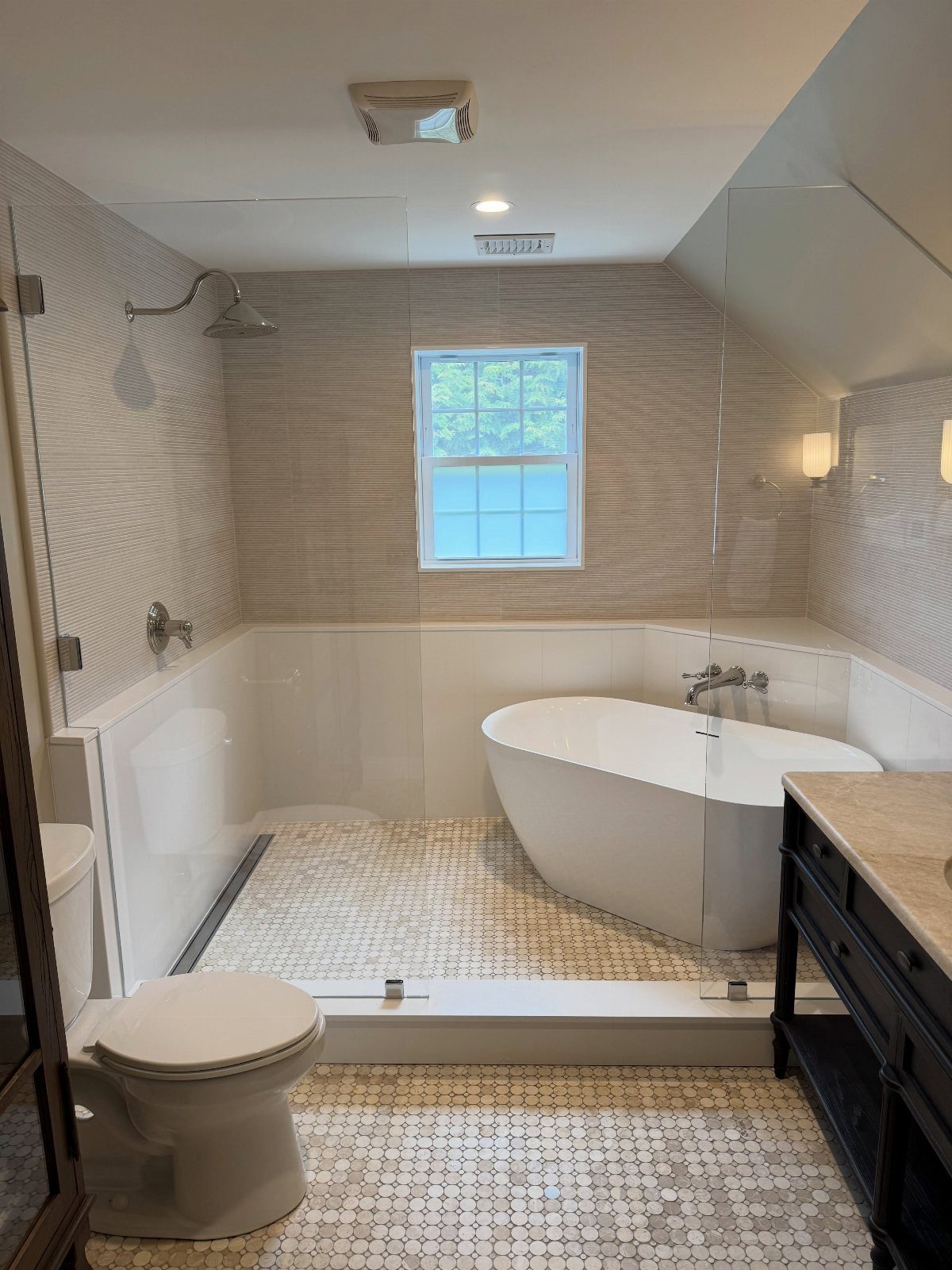 Modern large bathroom with freestanding tub, glass shower, and mosaic tile flooring.