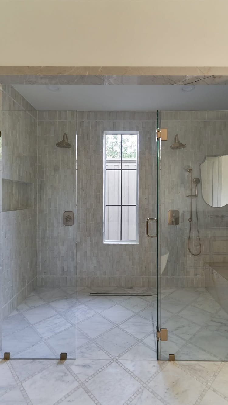 Walk-in shower with glass enclosure, grey tiles, and white marble diamond flooring.