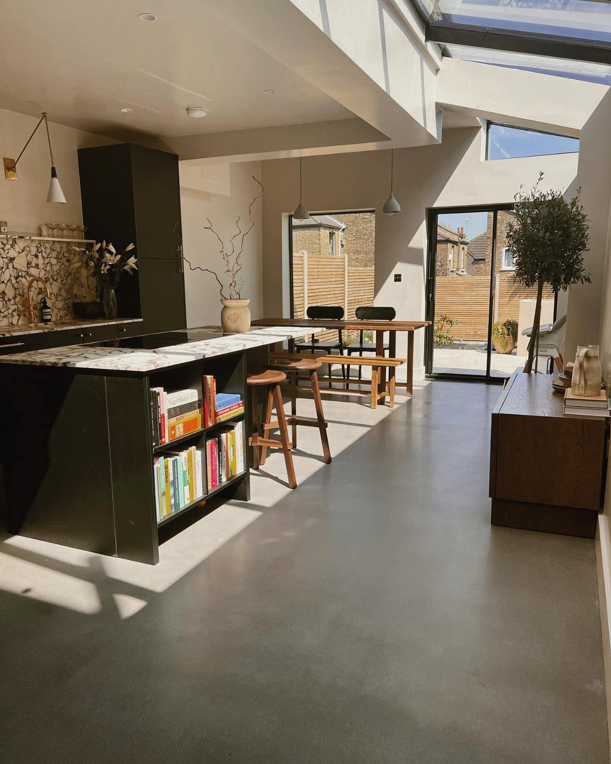 10 Mid Century Modern Kitchen Remodel Ideas for Your Home 7 Grey concrete floor in a modern kitchen with dark cabinets and wooden furniture.