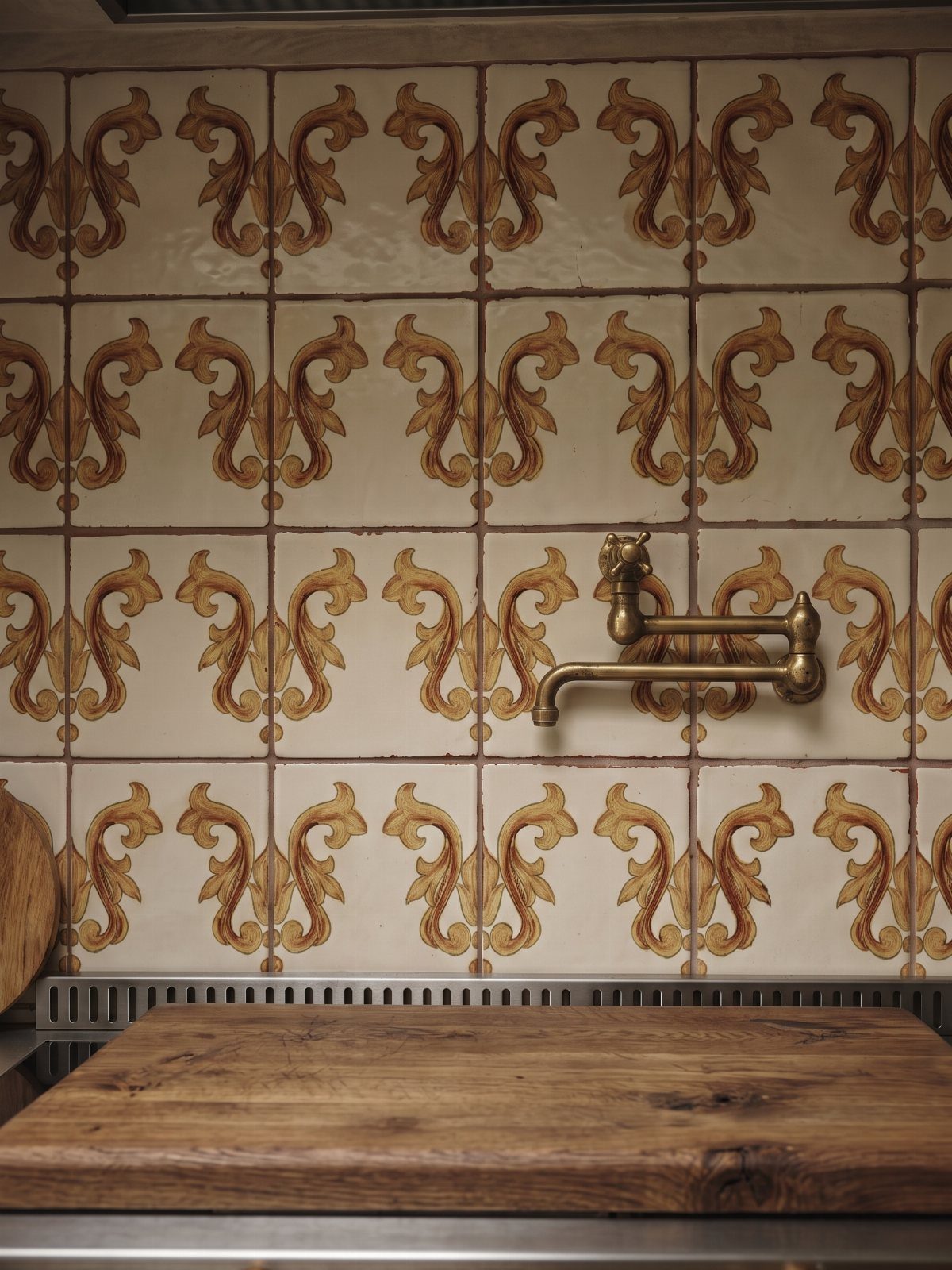 10 Mid Century Modern Kitchen Remodel Ideas for Your Home 4 Patterned backsplash with brown ornate tiles, brass faucet, and wooden cutting board.