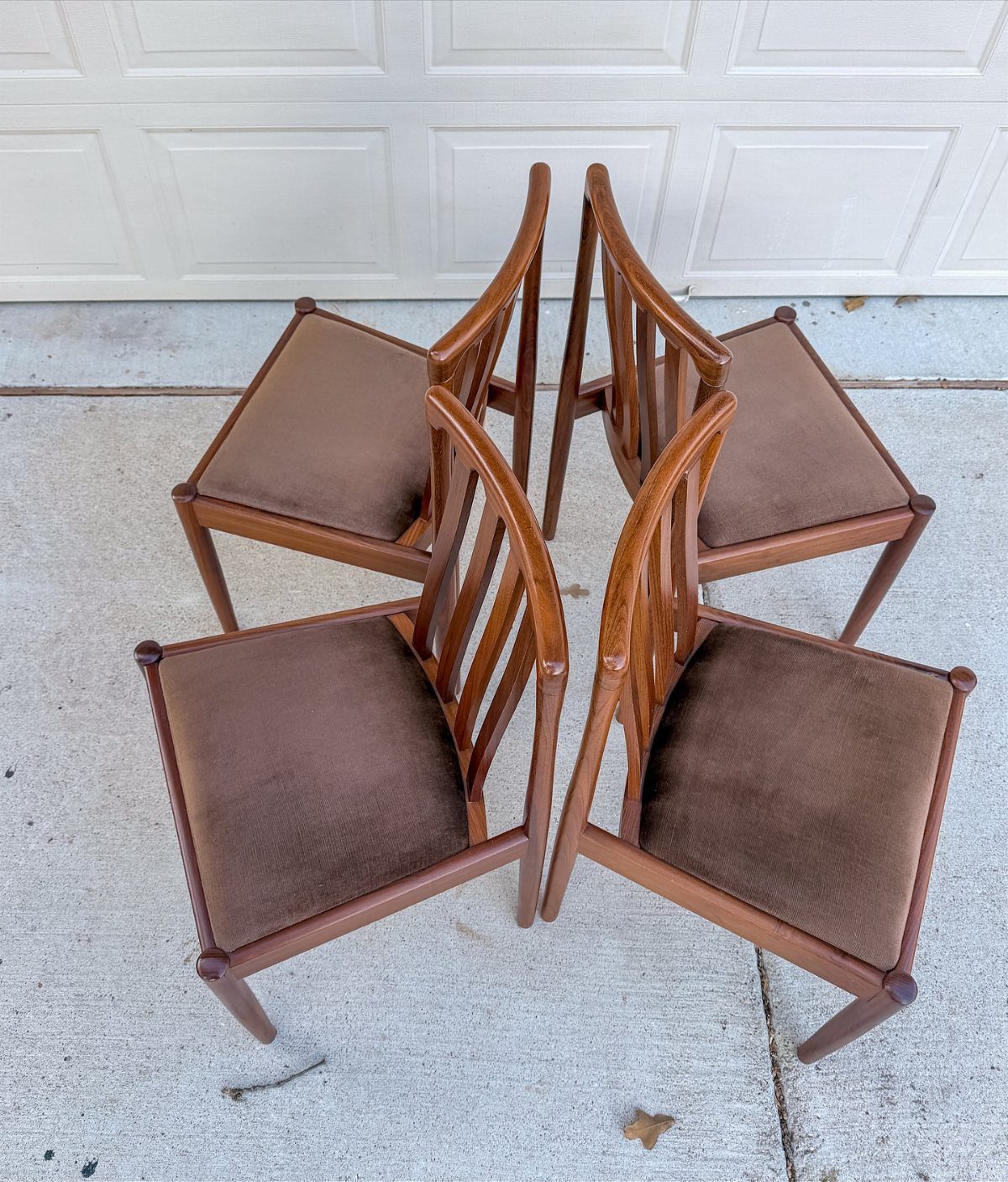 10 Mid Century Modern Kitchen Remodel Ideas for Your Home 10 Four mid-century modern wooden chairs with brown seats and tapered legs on concrete.