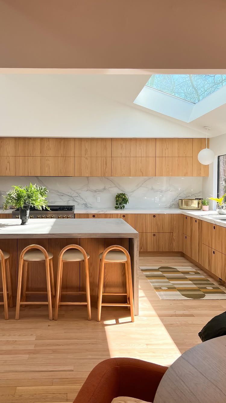 10 Mid Century Modern Kitchen Remodel Ideas for Your Home 9 Grey concrete kitchen island with wooden bar stools and light wood cabinetry.