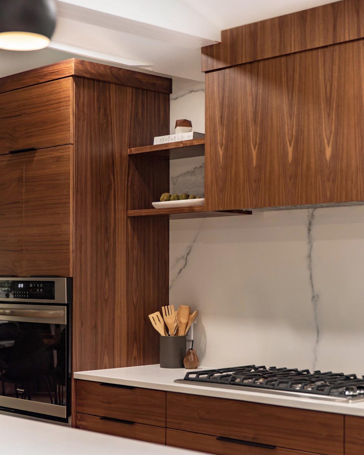 10 Mid Century Modern Kitchen Remodel Ideas for Your Home 5 Walnut wood kitchen cabinets with a small wood-framed floating shelf and marble backsplash.