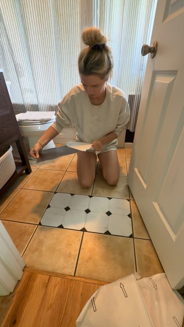 12 Mobile Home Master Bath Remodel Ideas and Moisture Tips 12 Woman kneeling on tan tile floor installing white and black patterned floor tiles.