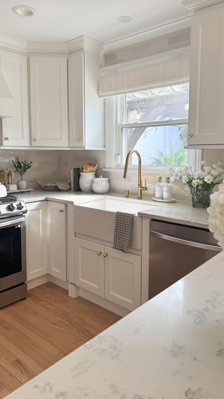 Neutral Kitchen Cabinets: 16 Colors From Greige to Black 5 Creamy white shaker cabinets with a white farmhouse sink and gold hardware in kitchen