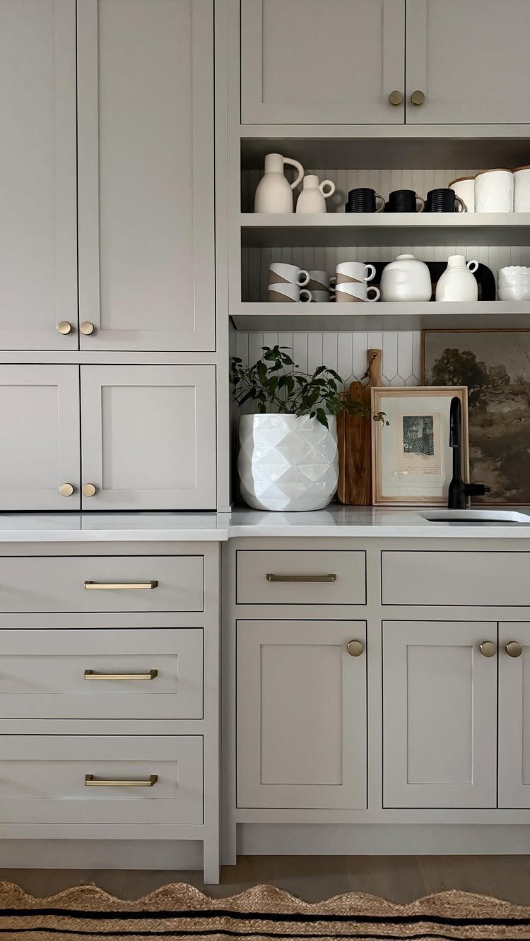 Neutral Kitchen Cabinets: 16 Colors From Greige to Black 13 Warm gray kitchen cabinets with gold handles and white countertops in a modern kitchen.