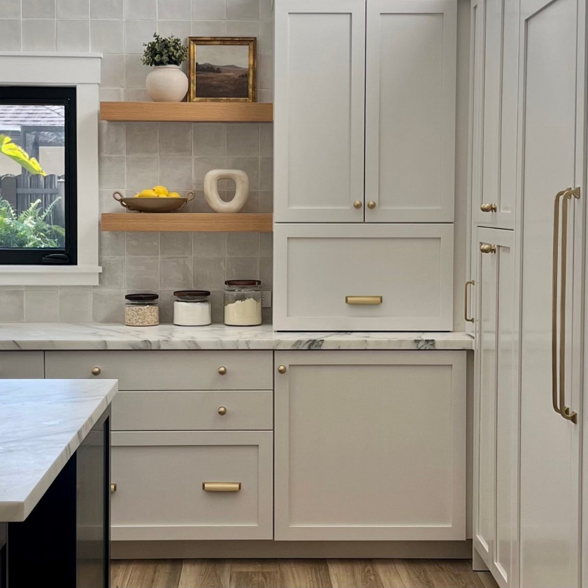 Neutral Kitchen Cabinets: 16 Colors From Greige to Black 11 Creamy white kitchen cabinets with gold handles and white marble countertops.