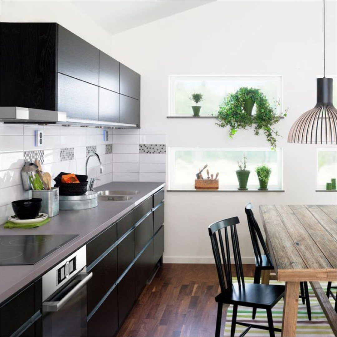 Modern one-wall kitchen with dark grey cabinets and a rustic wooden dining table.