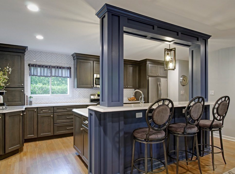Kitchen with dark brown cabinets and a blue peninsula with three bar stools.