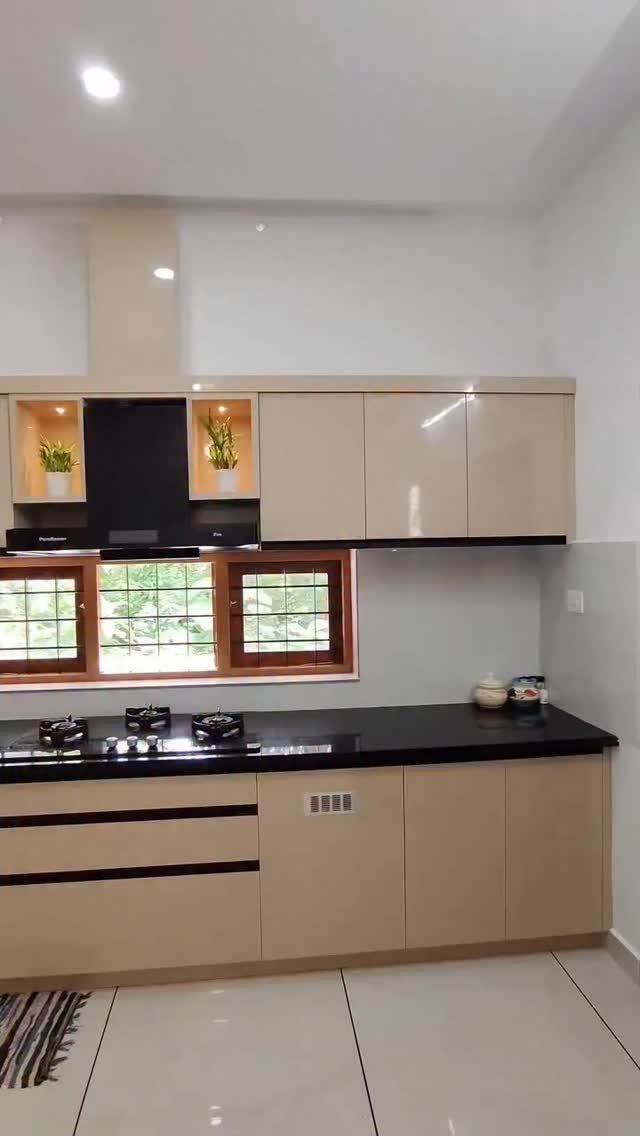 Beige flat-front kitchen cabinets with black countertops in a minimalist one-wall layout.