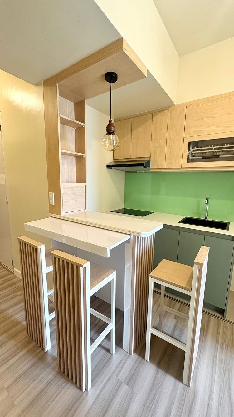 White bar table with wooden slat stools attached to a small modern kitchen counter.