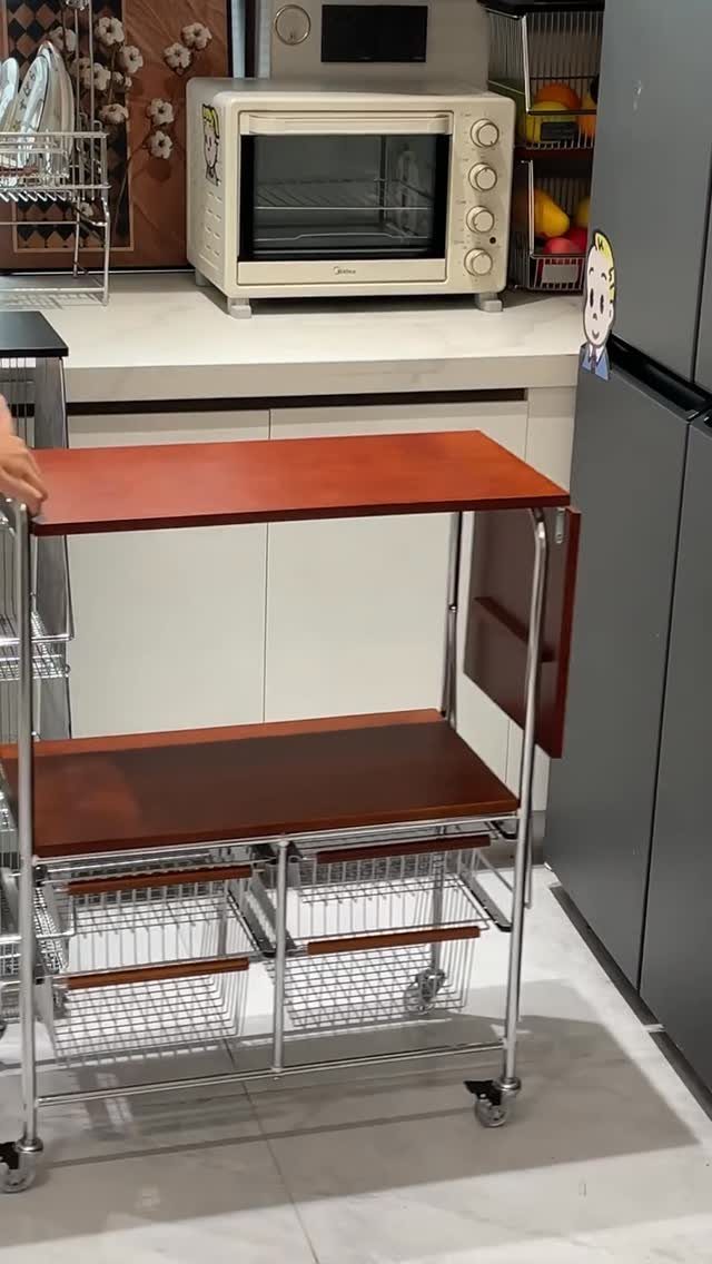 Rolling kitchen cart with wooden shelves and chrome frame in a modern kitchen.