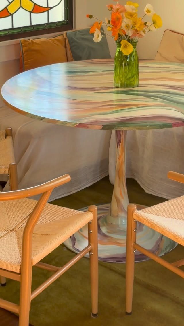 Painting Kitchen Table Ideas: 11 Looks From Yellow to Black 9 Round pedestal table with colorful abstract swirl painting and a vase of flowers
