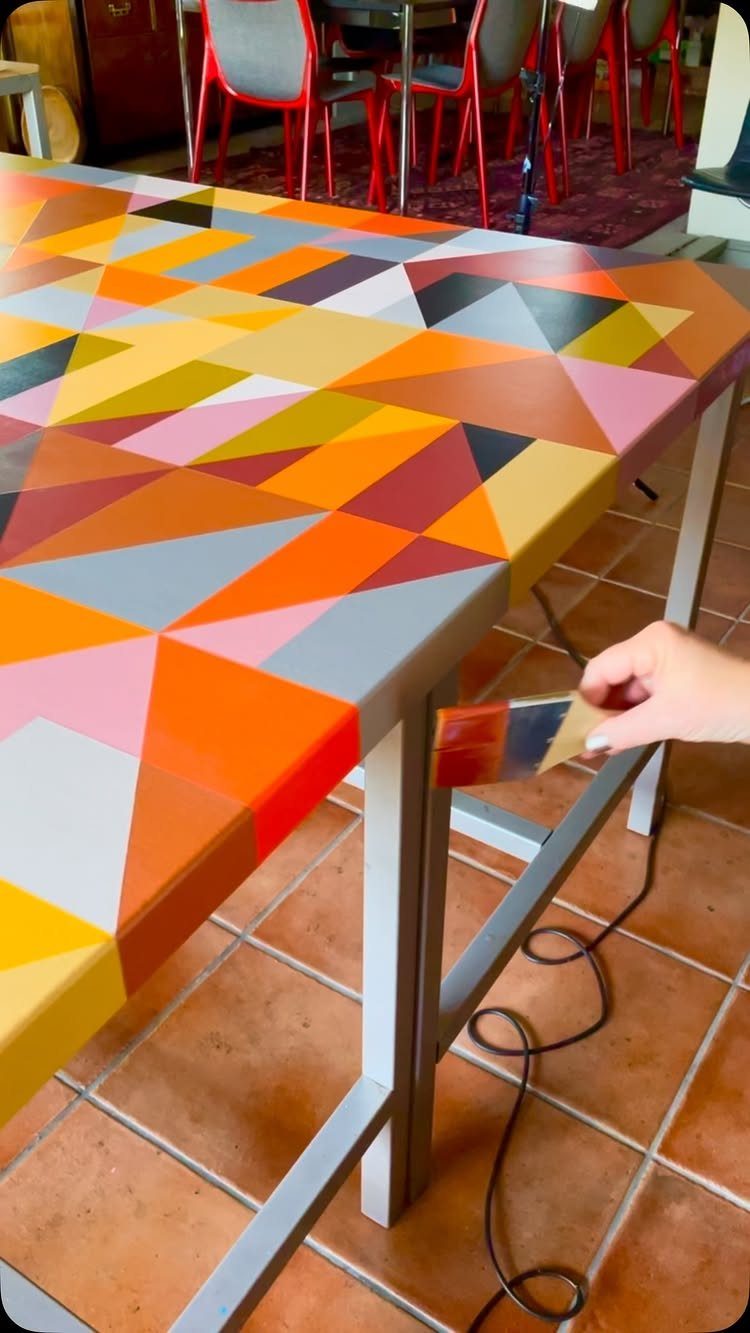 Painting Kitchen Table Ideas: 11 Looks From Yellow to Black 5 Colorful geometric pattern painted on a kitchen table being finished with a brush.