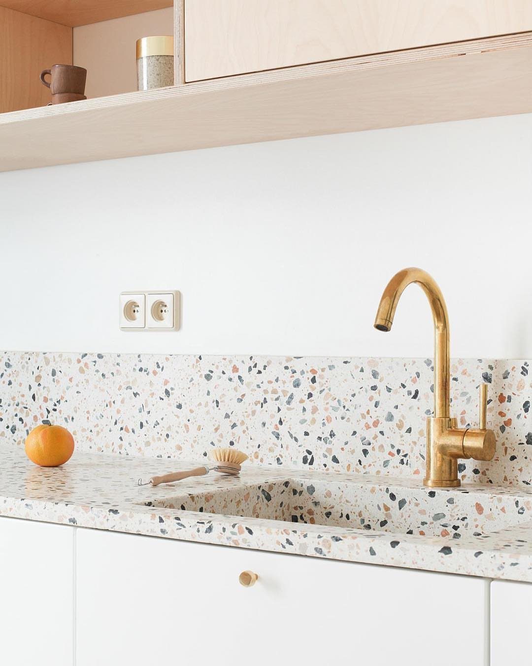 15 Ranch Style House Kitchen Remodel Ideas, Retro to Modern 7 Terrazzo backsplash and countertop with a gold faucet and white kitchen cabinets.