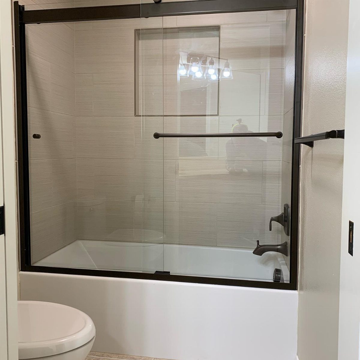 17 Remodeling Old House Ideas for Kitchens, Baths, Offices 1 White bathtub with black framed sliding glass doors and modern black fixtures.