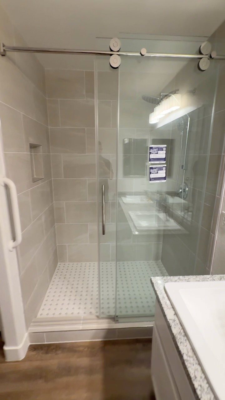 17 Remodeling Old House Ideas for Kitchens, Baths, Offices 4 Walk-in shower with glass sliding doors and grey tiles in a modern bathroom.
