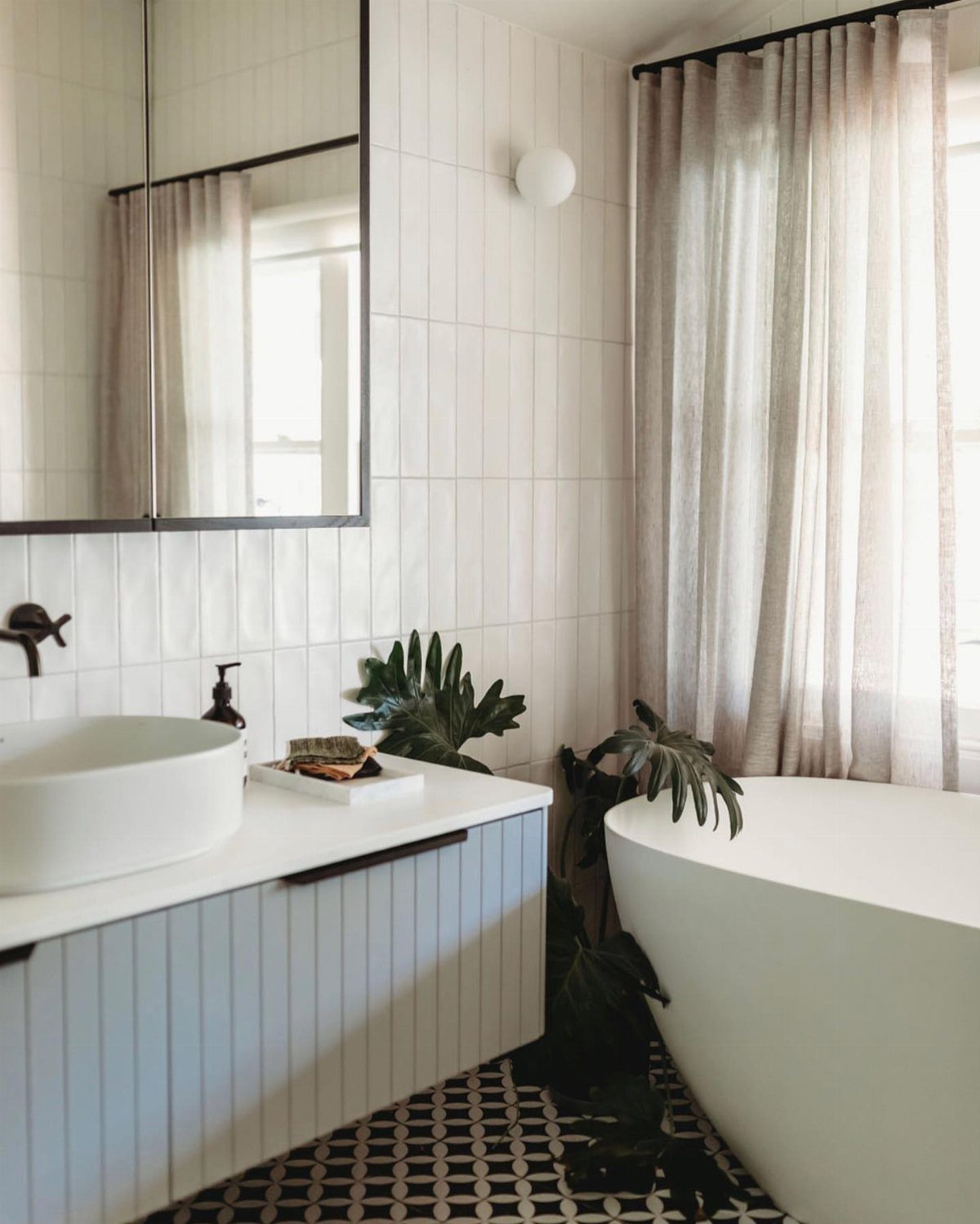 White ceramic wall tiles in a bright bathroom with a freestanding tub and vanity.