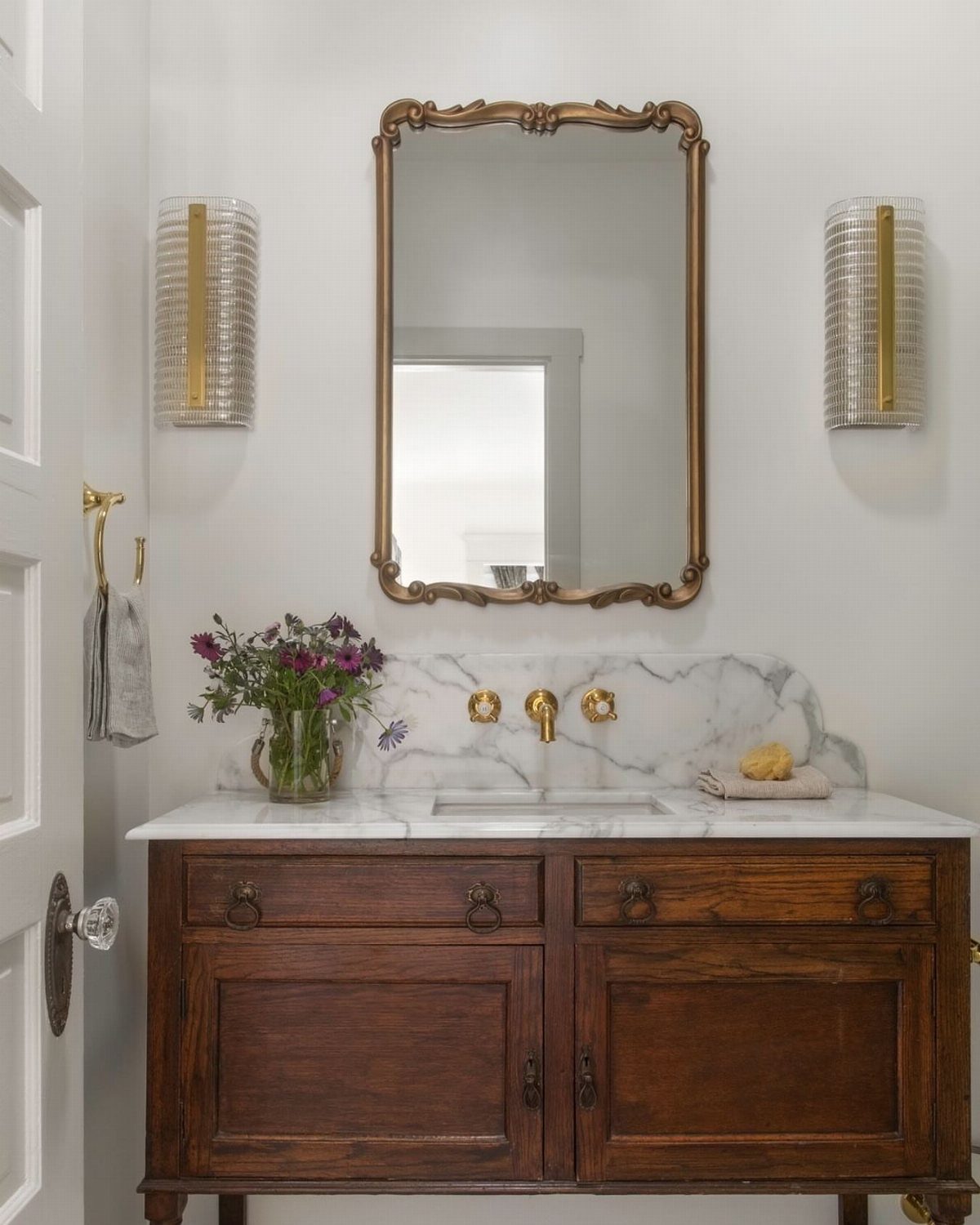 Antique dark wood dresser converted into a bathroom vanity with a white marble top.