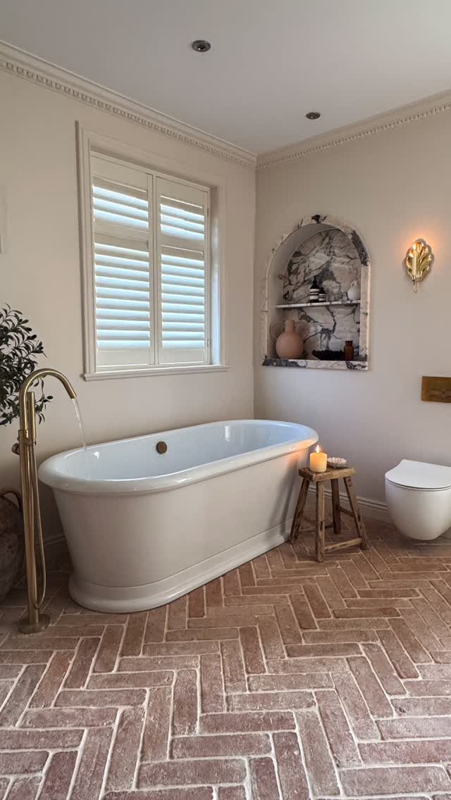 Terracotta floor tiles in a herringbone pattern in a neutral rustic bathroom.