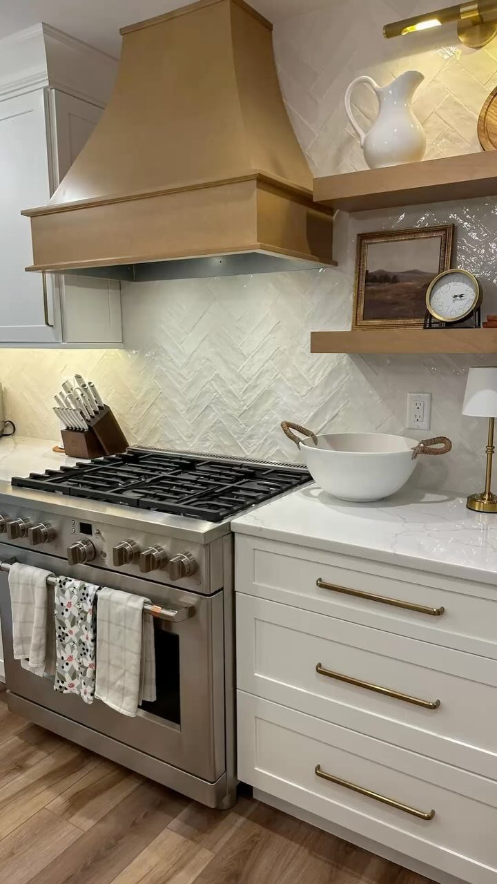 Rustic wooden floating shelves in a kitchen with a gold range hood and stove.