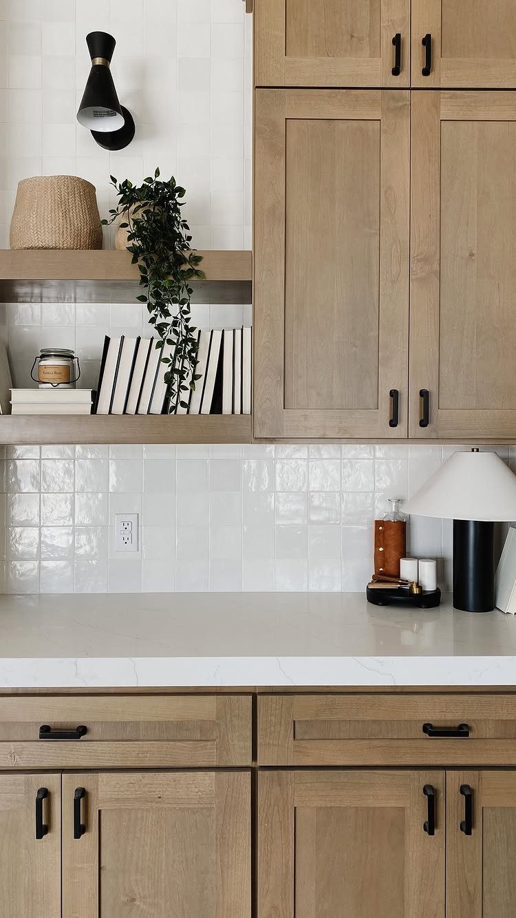 Light wood kitchen cabinets and open shelving with cookbooks and a green plant.